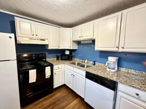 a kitchen with white cabinets and a black appliance at Cottage 2 Lees Ford Marina in Nancy