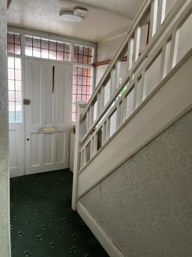 a hallway with stairs and a white door and a window at Leicester UK Room 2 Edward House in Leicester