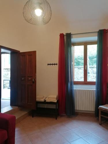a living room with red curtains and a window at appartamento Papaveri di Casa Mosaico in Volterra