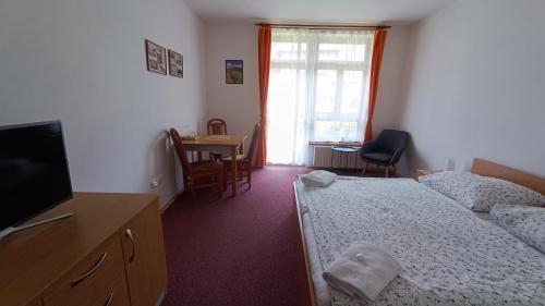 a room with two beds and a television and a table at Penzion Duncan in Janske Lazne