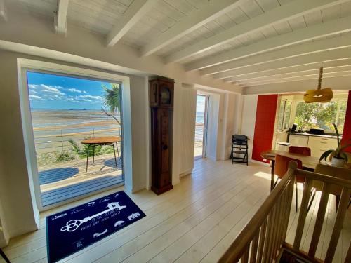 a room with a balcony with a view of the beach at Cottage Pêcheur + Annexe 12pers vue Mont St-Michel in Champeaux
