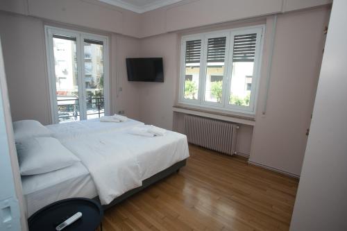 a white bedroom with a bed and two windows at Elegant Apartment Downtown Athens II in Athens