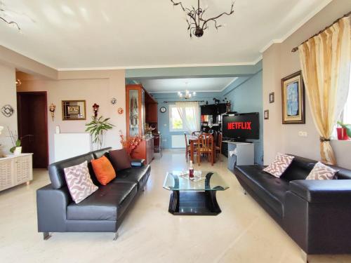 a living room with black leather couches and a tv at Sophia's Ηouse in Preveza