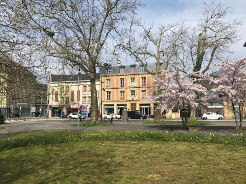 a park withakura trees in front of a building at Hotel Bar Restaurant Couleurs Sud in Charleville-Mézières