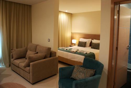 um quarto de hotel com uma cama e uma cadeira em Beramar Hotel em Praia