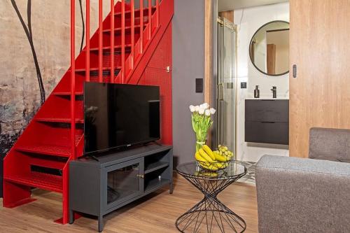 sala de estar con TV y escalera roja en Budget Apartment Gliwice 1min from Main Square, en Gliwice