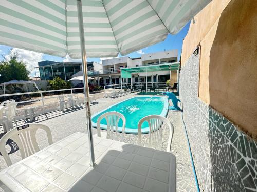 a swimming pool with chairs and an umbrella at Dellas Pousada in Maragogi
