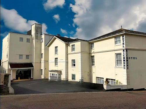 a large white building with a parking lot at Richmond Hotel in Torquay