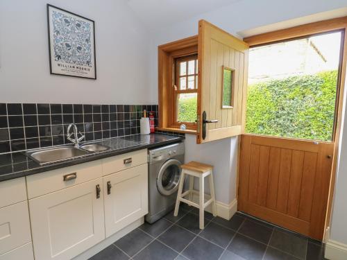 a kitchen with a sink and a washing machine at Plum Tree Cottage in Castleton