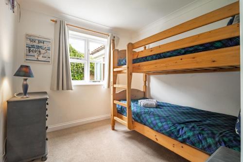 a bedroom with two bunk beds and a window at Brambles in Brancaster
