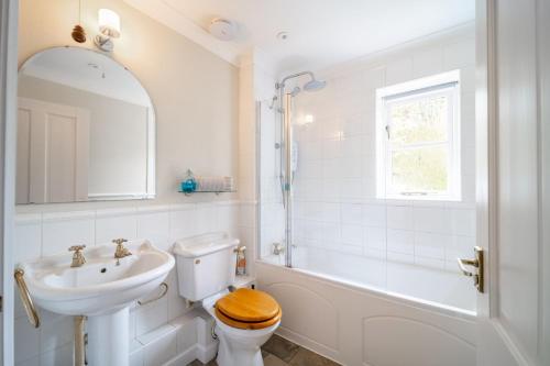 a white bathroom with a sink and a toilet and a tub at Brambles in Brancaster