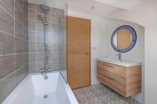 a bathroom with a tub and a sink and a mirror at 500m Plage des Libraires - Maison 4 chambres in Pornichet