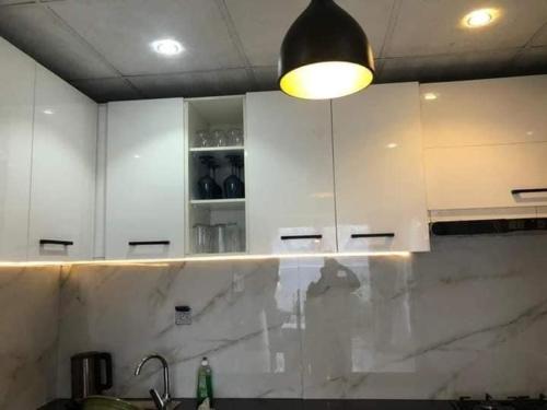 a kitchen with white cabinets and a light above a counter at Villa trois chambres avec piscine in Cotonou