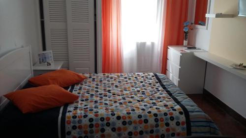 a small bedroom with a bed with an orange curtain at Alojamento Bela Vista in Lajes do Pico