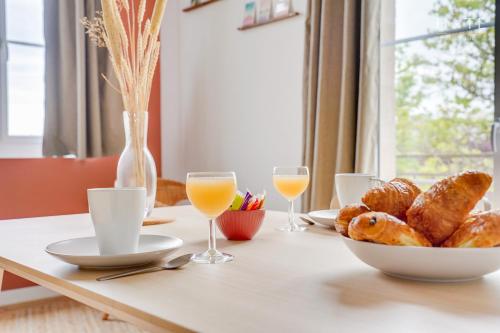 een tafel met een bord brood en glazen sinaasappelsap bij Appartement rénové, situation idéale à Libourne in Libourne