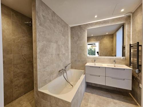 une salle de bain avec une baignoire, un lavabo et un miroir dans l'établissement Villa Cap d'Antibes, à Antibes