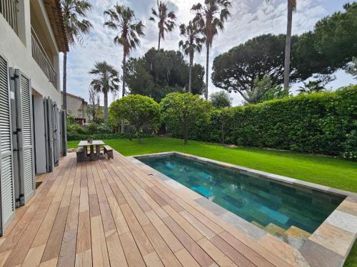 une cour arrière avec une piscine et une terrasse en bois dans l'établissement Villa Cap d'Antibes, à Antibes