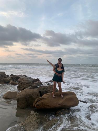 Una mujer parada en una roca en el océano en Casa heysol en Bahía de Caráquez