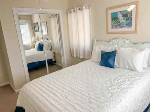 um quarto com uma grande cama branca e um espelho em Beach Bliss em Kill Devil Hills