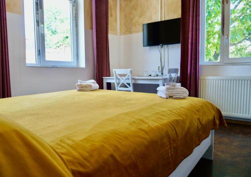 Un dormitorio con una gran cama amarilla con toallas. en Vila Alfredo, en Craiova