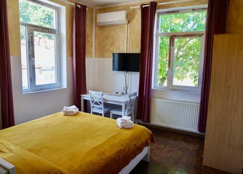 a bedroom with a yellow bed and two windows at Vila Alfredo in Craiova