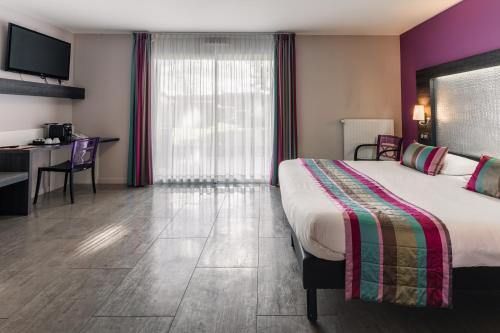 a hotel room with a large bed and a desk at The Originals Boutique, Hôtel Le Lion d'Or, Fougères Ouest in Maen Roch