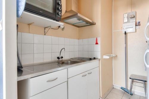une petite cuisine avec un évier et un micro-ondes dans l'établissement Parenthèse reposante tout près de la mer, à La Parée Preneau