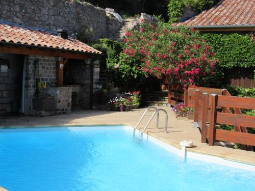 ein Swimmingpool mit einer Bank und einem Baum mit rosa Blüten in der Unterkunft La Grange in Vals-les-Bains