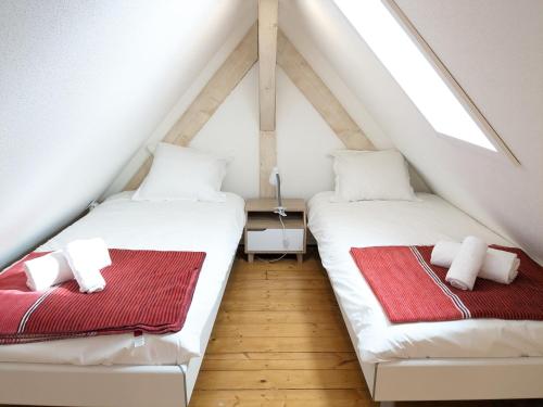 two beds in a attic room with a window at Appartement Le Ch'ti Alsacien in Eguisheim