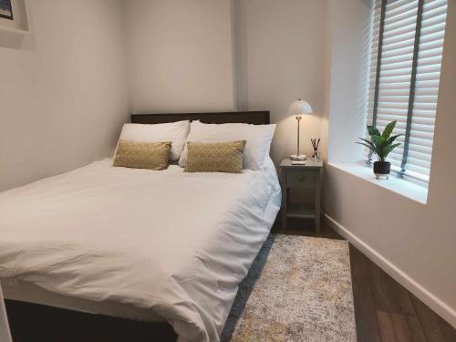 1 cama blanca en un dormitorio con ventana en Queen's Apartment in Cardigan, Cardigan Bay en Cardigan