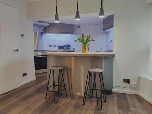 una cocina con 2 taburetes y una barra en Queen's Apartment in Cardigan, Cardigan Bay en Cardigan