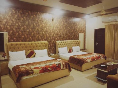 Royal Fort Executive Hotel Gulberg في لاهور: غرفة فندقية بسريرين واريكة