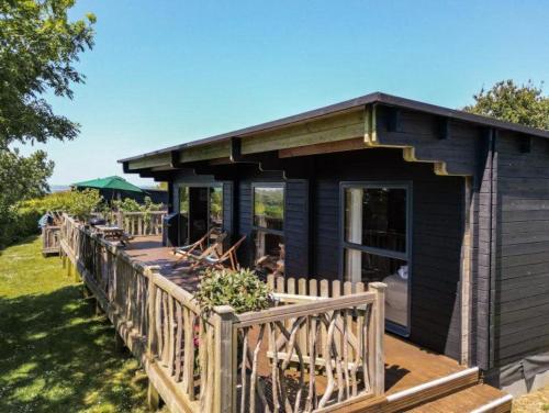 a small black house with a wooden deck at Wood Cabin 2 At Tapnell Farm in Yarmouth