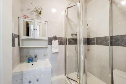a white bathroom with a shower and a sink at Indipendent flat with patio in Greenford