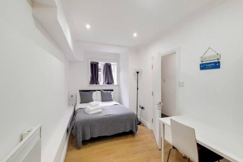 a white bedroom with a bed and a desk at Indipendent flat with patio in Greenford