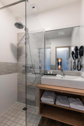 a bathroom with a sink and a shower at The Originals Boutique, Hôtel Le Lion d'Or, Fougères Ouest in Maen Roch