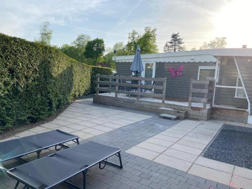 a patio with two picnic tables and an umbrella at Wellness chalet Putten Hottub & Sauna in het bos in Putten