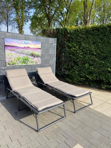 2 sillones sentados junto a una pared con una pintura en Luxe gerenoveerde L-chalet en Putten