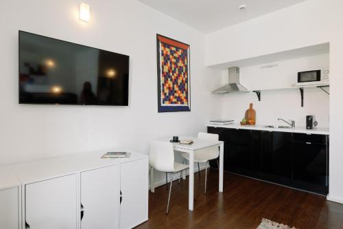 una cocina con armarios blancos y una mesa y sillas blancas. en Fine Arts Studios by Olala Homes, en Oporto