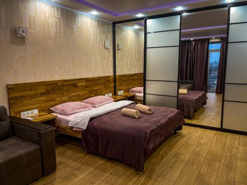 sypialnia z 2 łóżkami, kanapą i lustrem w obiekcie Новобудова в Центрі біля набережної w mieście Krzemieńczuk