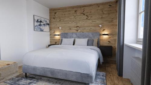a bedroom with a white bed and a wooden wall at Das Lambacher in Oberaudorf