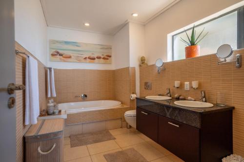 ウムドロティにあるLuxury Beachfront Apartment - 30 Degrees Umdlotiのバスルーム(洗面台2台、バスタブ、トイレ付)