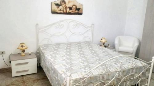 1 dormitorio con 1 cama blanca y 1 silla en 2 bedrooms house at Patu 250 m away from the beach with sea view and terrace, en Patù