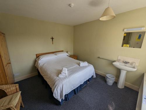 The Shrine of Our Lady of Walsingham في ليتل والشنغهام: غرفة نوم صغيرة بها سرير ومغسلة