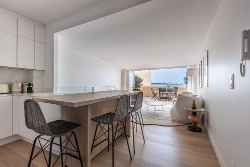 une cuisine avec des placards blancs et un îlot avec des tabourets de bar dans l'établissement A3B047 TRIPLEX MODERNE TERRASSE vue MER, à Cannes