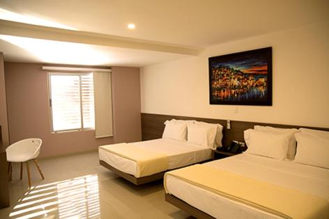 a hotel room with two beds and a window at Hotel Mio Boutique in Cúcuta