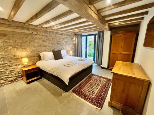 a bedroom with a bed and a stone wall at The Cart House - Rural Retreat in Hereford