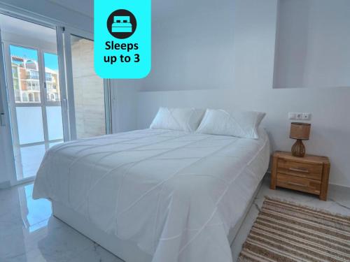 Blue Sea Unique Apartment in Torrevieja - Short walk to the beach في توريفايجا: سرير أبيض في غرفة نوم بيضاء مع موقف ليلي