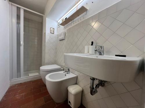 a white bathroom with a sink and a toilet at Vicolo della Scala Rooms in Cortona