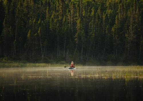 a person in a boat on a body of water at Auberge de Montagne des Chic-Chocs Mountain Lodge - Sepaq in Sainte-Anne-des-Monts